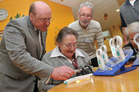 Prof. Dr. Burkhard Dick zeigt Bewohnerin Irmgard Dudek und Heimleiter Theo Elbers wie die neue Sehhilfe verwendet wird. 