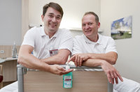 Die Hygienefachkräfte Martin Niebius (li.) und Michael Bosmanns testen den Desinfektionsmittelspender am Krankenbett